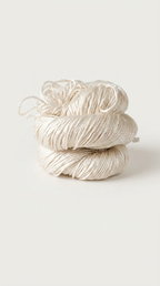 one skein of white yarn stacked on a light gray background