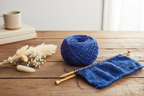 Lifestyle image of royal blue sari silk yarn with knitting needles and scarf